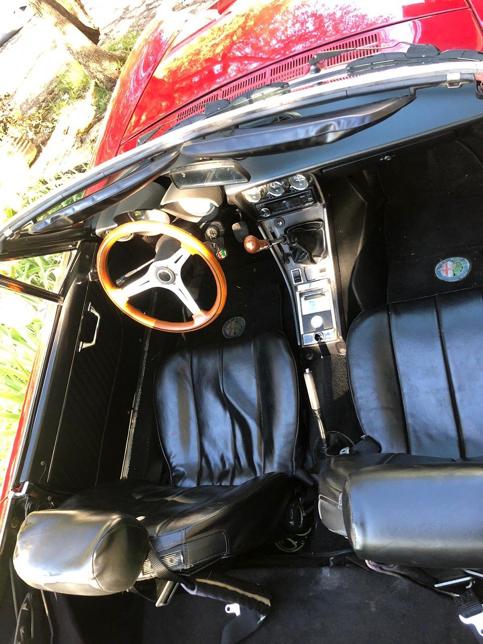 Overhead interior shot of a red Alfa Romeo Spider convertible with wood steering wheel
